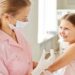 Adorable girl looking at nurse while she making her an injection in clinics