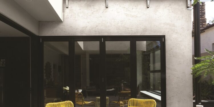 Pair of yellow cane outdoor chairs on wooden deck in contemporary courtyard
