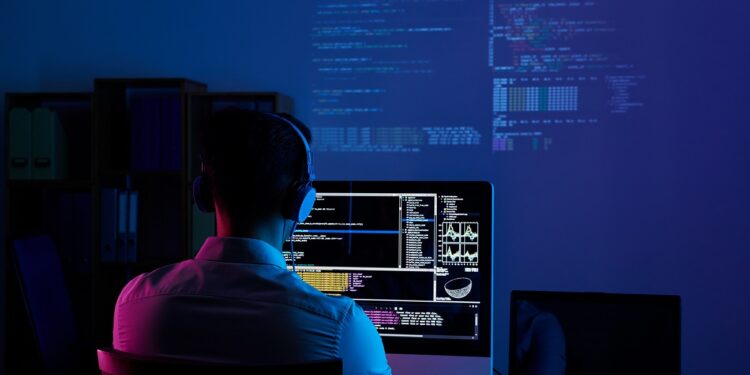 Developer working on code late at night, view from the back
