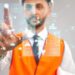 Close up of architect wearing reflective vest and helmet. Selective focus of digital tactile charts screen, man touching virtual icon on projection. Concept of digitalization, construction.
