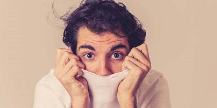 Young man feeling frightened and shocked making scared gestures in fear and anxiety. Terrified and desperate trying to cover himself. Copy space. People Human expressions and emotional reactions.