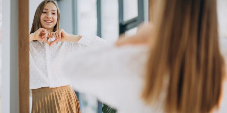 Pretty young woman in casual outfit looking into mirror