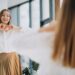 Pretty young woman in casual outfit looking into mirror