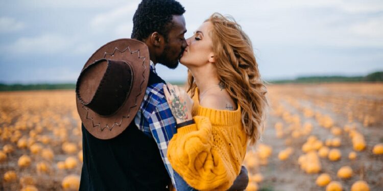 A young interracial couple kisses in a pumpkin field, close-up.; Shutterstock ID 1626962086; purchase_order: 09262022; job: Editorial Associate; client: Ellie Spencer-Failes; other: