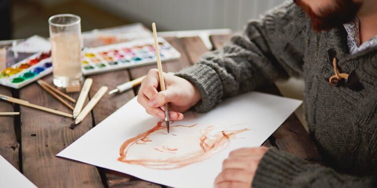 Close-up of young man in sweater drawing beautiful female