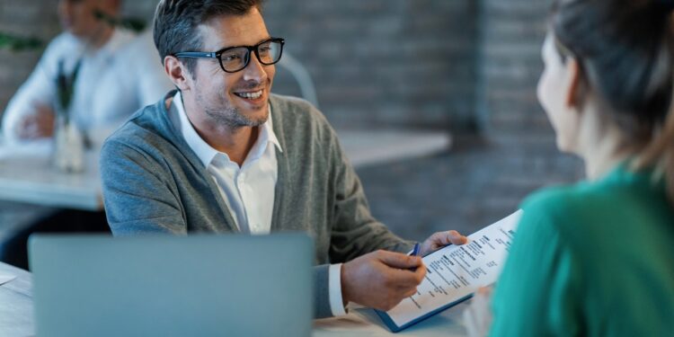 Happy businessman talking to his colleague while going through financial reports in the office.