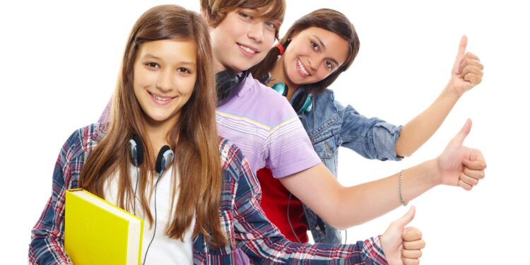 Row of teens with headphones showing thumbs up and smiling at camera