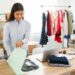 I got a new online order from a client. Happy female entrepreneur smiling while preparing to ship a package from her fashion clothing shop