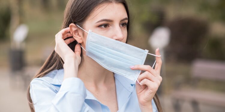 Portrait of a young and beautiful girl who puts on a medical mask on her face Health care