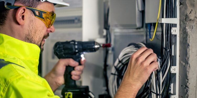 Man, an electrical technician working in a switchboard with fuses. Installation and connection of electrical equipment.