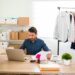 Focused business owner sitting at his office desk and updating the products and new fashion clothes on his online e-commerce