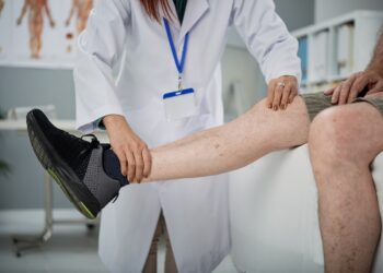 Physiotherapist checking hurt leg of senior man
