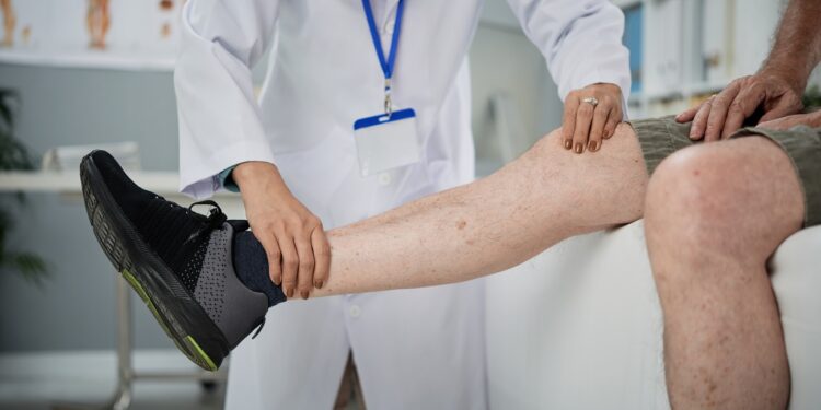 Physiotherapist checking hurt leg of senior man