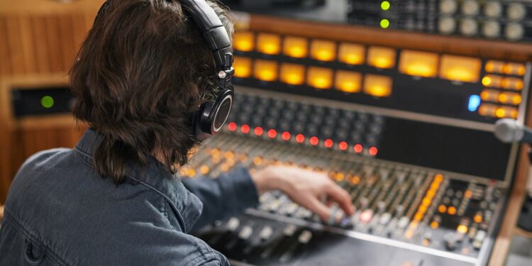 High angle at music producer operating audio workstation in professional recording studio, copy space