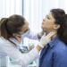 Endocrinologist examining throat of young woman in clinic. Women with thyroid gland test . Endocrinology, hormones and treatment. Inflammation of the sore throat
