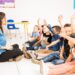 Profile view of a group of preschool students raising their hands and trying to participate at school