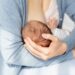 Lactation Concept. Closeup Shot Of Unrecognizable Woman Breastfeeding Newborn Baby At Home, Supporting His Head With Hand, Infant Child Eating Mom's Breast Milk, Cropped Image