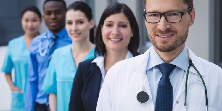 Portrait of smiling doctors standing in row at hospital premises