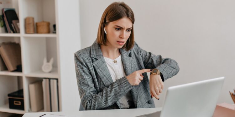 Dissatisfied lady boss talks on video and shows her watch, reminding her subordinates of deadline