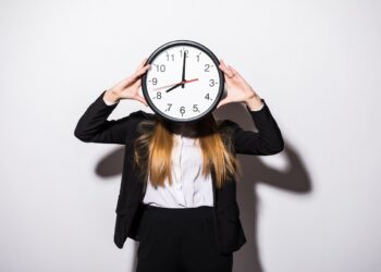 Beautiful business woman holding in hands clock isolated on white background