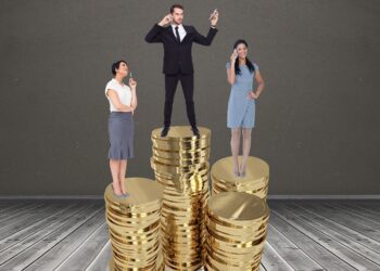 Digital composite image of businesspeople standing on stacked coins against grey background