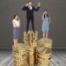 Digital composite image of businesspeople standing on stacked coins against grey background
