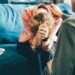 Sad woman cries and wipes nose with tissue sitting on blue sofa at appointment with professional psychologist in light clinic office close view