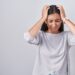 Young hispanic woman standing over white background suffering from headache desperate and stressed because pain and migraine. hands on head.