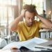 International Afro American student feeling stressed, keeping hands on his head, staring at laptop screen in frustration and despair after he made serious mistake in calculation, working on research