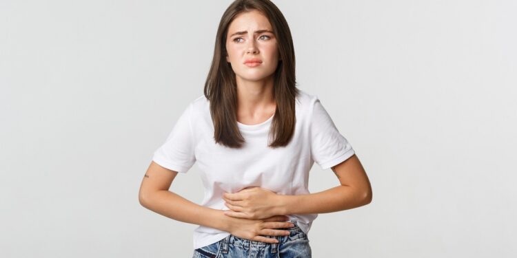 Woman having stomach ache, bending and holding hands on belly, discomfort from menstrual cramps.