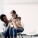 Young distraught woman being consoled by African American woman at community center. Copy space.