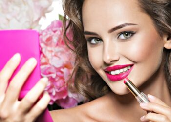 Smiling Woman applying lipstick. Beautiful girl makes makeup