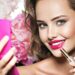 Smiling Woman applying lipstick. Beautiful girl makes makeup