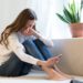 Young woman cry reading sms on smartphone suffer from breakup with boyfriend. Frustrated female in tears on couch with mobile phone in hand get message with bad news, betrayal from friend or accident