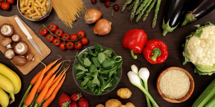 Photo of a table top full of fresh vegetables, fruit, and other healthy foods.