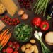 Photo of a table top full of fresh vegetables, fruit, and other healthy foods.