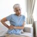 Unhealthy mature woman holding belly, feeling discomfort, health problem concept, unhappy older female sitting on bed, suffering from stomachache, food poisoning, gastritis, abdominal pain, climax