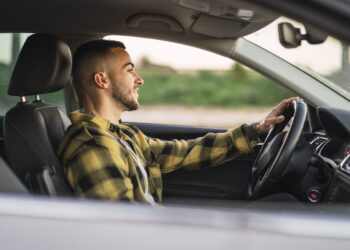 A shallow focus shot of a handsome Spanish Caucasian man sitting behind the wheel of a modern car
