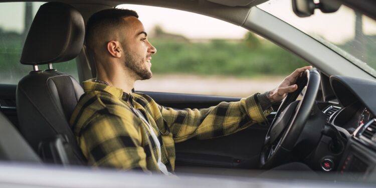 A shallow focus shot of a handsome Spanish Caucasian man sitting behind the wheel of a modern car