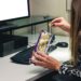 side view unrecognizable female office worker eating junk food while working, looking at computer screen, in customer service office.