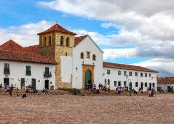 Villa de Leyva, Colombia - The church on the Plaza Mayor of the historic 16th Century town of Villa de Leyva. Founded in 1572 and located at an altitude of just over 7000 feet above mean sea level on the Andes Mountains, Villa de Leyva was declared a National Monument by the Colombian Government in 1954 to protect its colonial architecture and heritage. It is located in the Department of Boyacá. The square is the largest town square in Colombia. Colombians visiting the town and local residents are seen on the square just sitting and relaxing, chatting with friends or going about their routine chores. In the background are the Andes Mountains. The Town was one of the locations for the movie Cobra Verde by Werner Herzog and the Spanish language Soap Opera Zorro. Photo shot in the afternoon sunlight; horizontal format. Copy space.