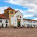 Villa de Leyva, Colombia - The church on the Plaza Mayor of the historic 16th Century town of Villa de Leyva. Founded in 1572 and located at an altitude of just over 7000 feet above mean sea level on the Andes Mountains, Villa de Leyva was declared a National Monument by the Colombian Government in 1954 to protect its colonial architecture and heritage. It is located in the Department of Boyacá. The square is the largest town square in Colombia. Colombians visiting the town and local residents are seen on the square just sitting and relaxing, chatting with friends or going about their routine chores. In the background are the Andes Mountains. The Town was one of the locations for the movie Cobra Verde by Werner Herzog and the Spanish language Soap Opera Zorro. Photo shot in the afternoon sunlight; horizontal format. Copy space.