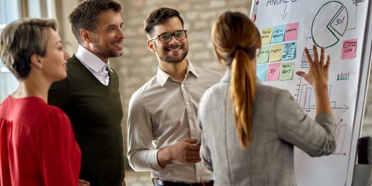 Happy business team cooperating while analyzing their business progress on whiteboard in the office.
