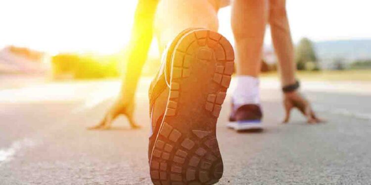 Athlete runner feet running on treadmill closeup on shoe.Mans fitness with the sun effect in the background and open space around him