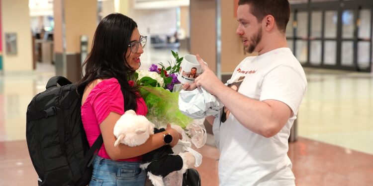 Clayton tearfully presents a custom coffee mug to Anali at the airport in Kentucky.