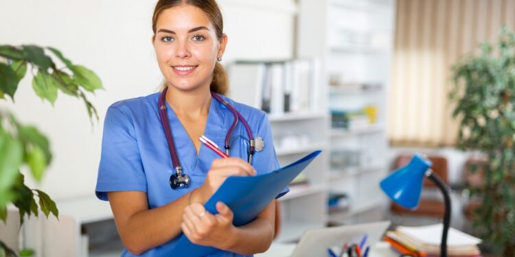 Positive confident young female doctor working in the clinic makes important notes on a tablet while standing in the 
resident's office. Close-up portrait