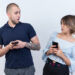 young beautiful couple in casual clothes man and woman holding smartphones looking at each other confused and very anxious standing over white background