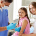 Smiling girl looking at camera while doctor making her an injection in clinics