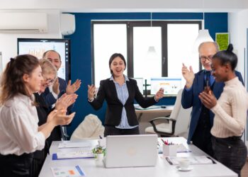 Motivated happy diverse business team people clapping celebrating success at corporate meeting. Multiethnical partners coworkers celebrate successful teamwork result at company briefing