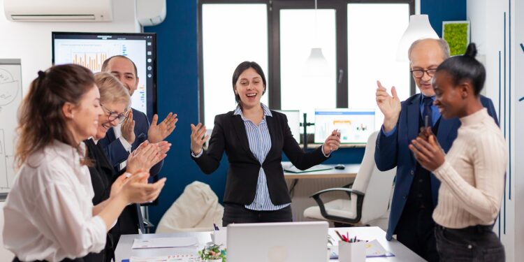 Motivated happy diverse business team people clapping celebrating success at corporate meeting. Multiethnical partners coworkers celebrate successful teamwork result at company briefing